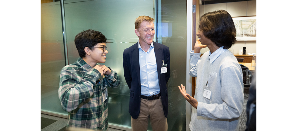 Image of one of the competition winners talking while gesturing with his hands to Tim Peake and the other winner, who appear to be laughing
